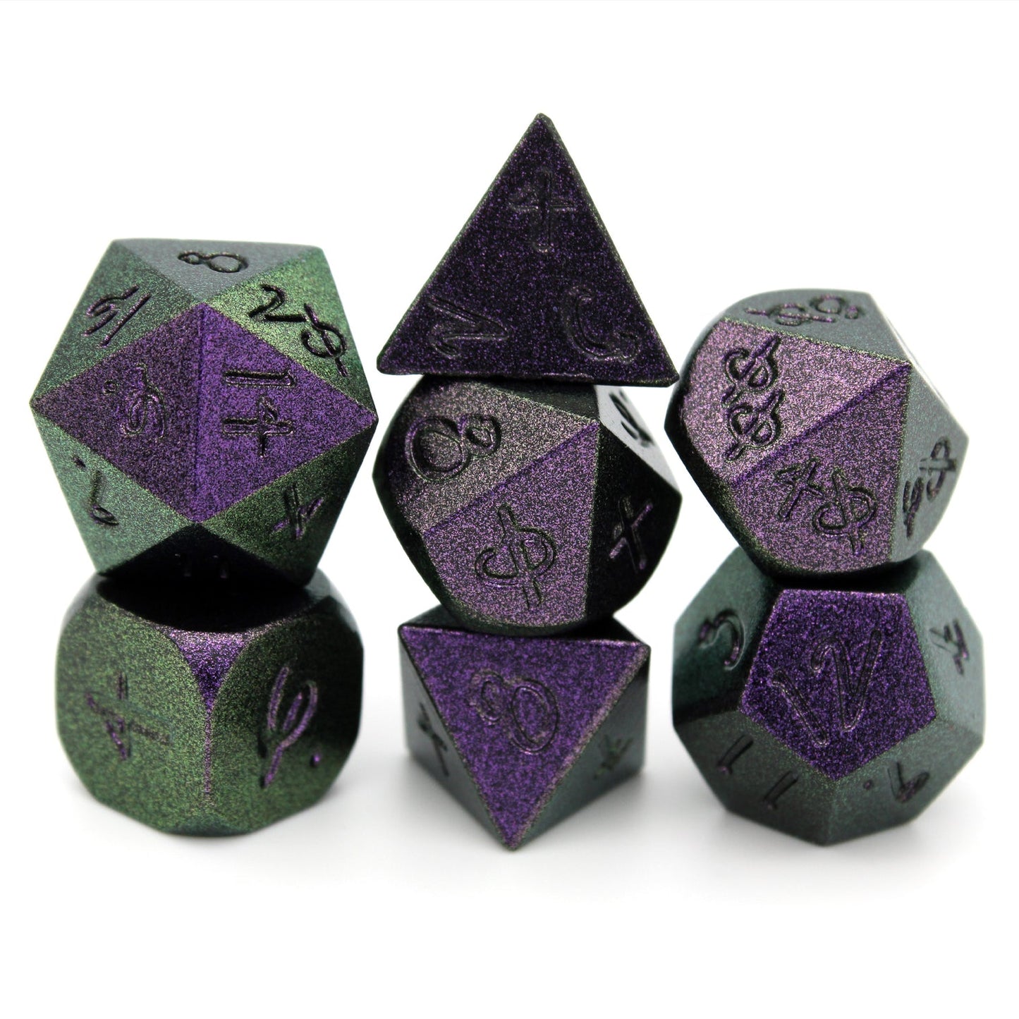 Set of 7 polyhedral dice with matte green and purply glittery finish and black numbering in Aabria Iyengar's handwriting.